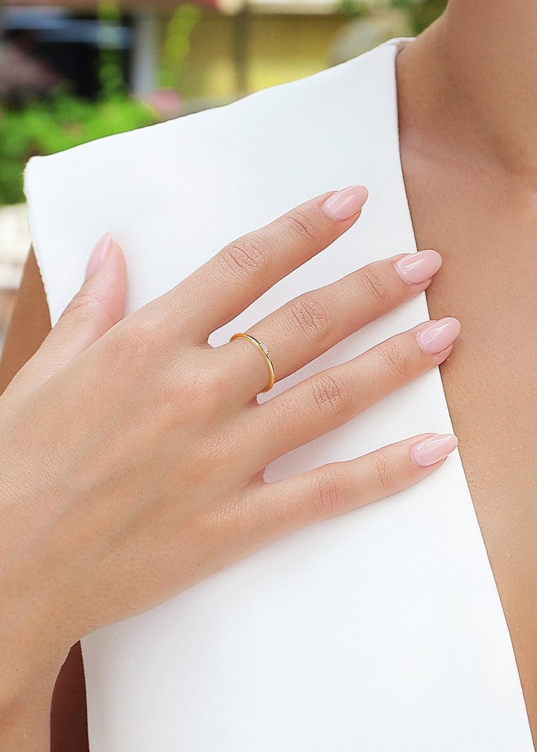 Close-up of a hand wearing a yellow gold ring with a baguette-cut diamond bar