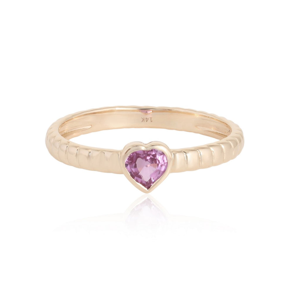 Yellow gold ring with heart-shaped pink gemstone and ridged band on a white background