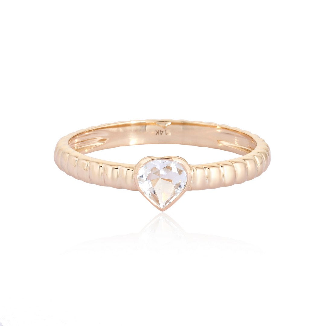 Yellow gold ring with heart-shaped white gemstone and ridged band on a white background