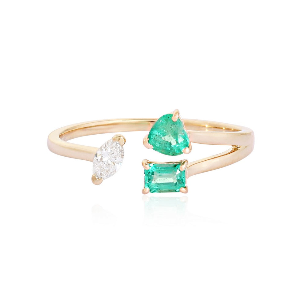 Yellow gold open bypass ring with a pear-shaped diamond and green emerald stones on a white background
