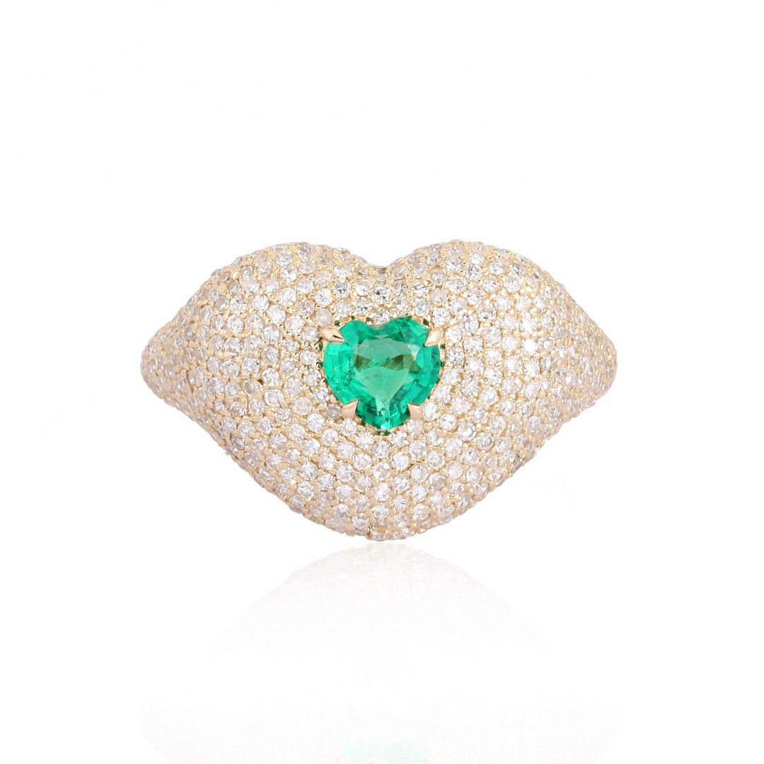 Yellow gold lips-shaped ring encrusted with diamonds and a heart-shaped green emerald at the center on a white background