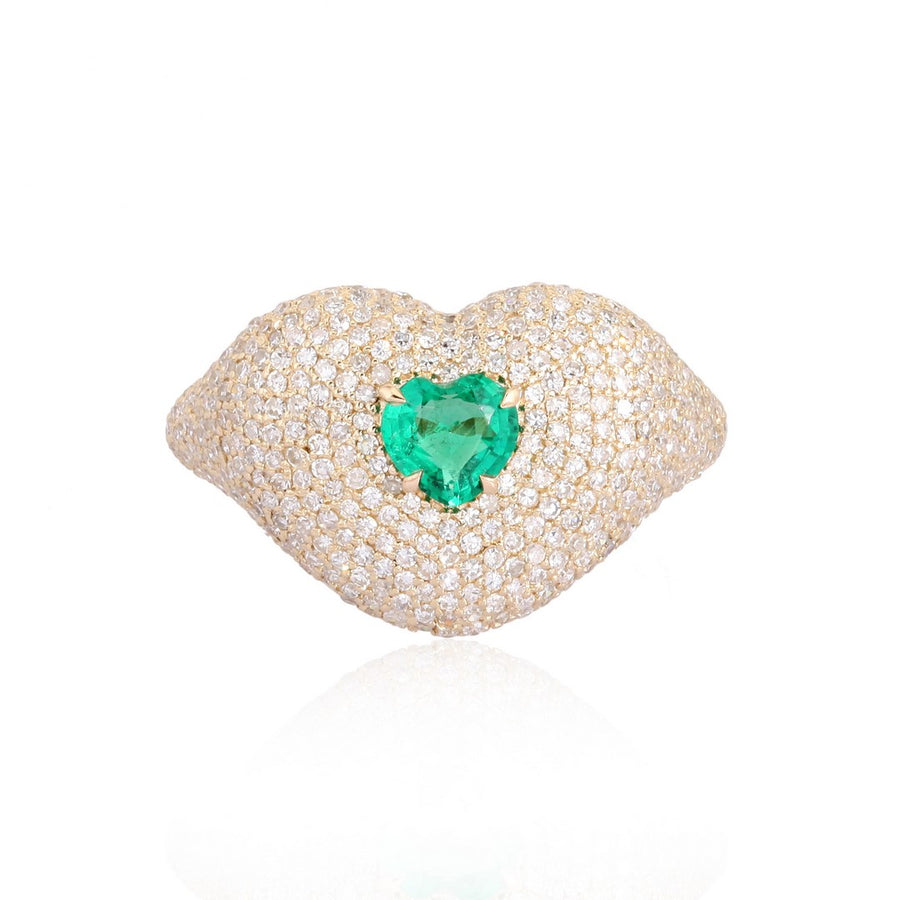 Yellow gold lips-shaped ring encrusted with diamonds and a heart-shaped green emerald at the center on a white background