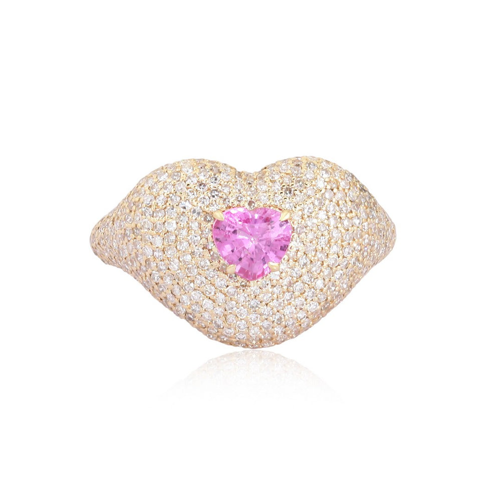 Yellow gold lips-shaped ring encrusted with diamonds and a heart-shaped pink gemstone at the center on a white background