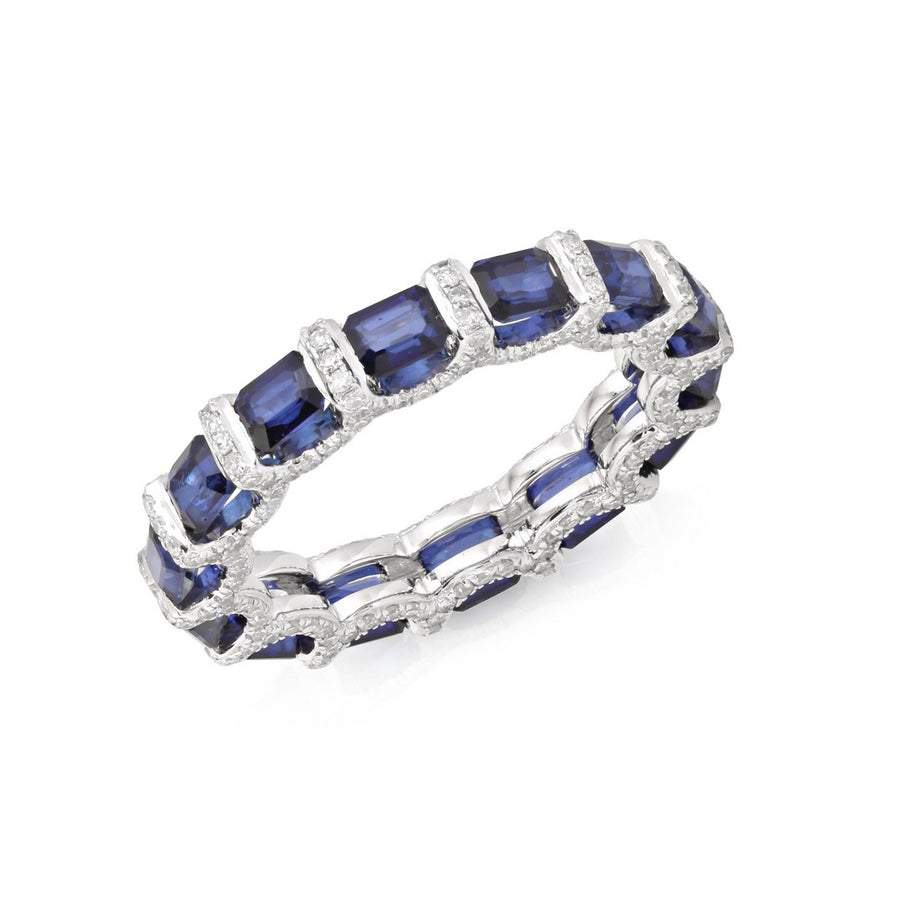 White gold eternity band with rectangular blue sapphires and diamond accents on a white background