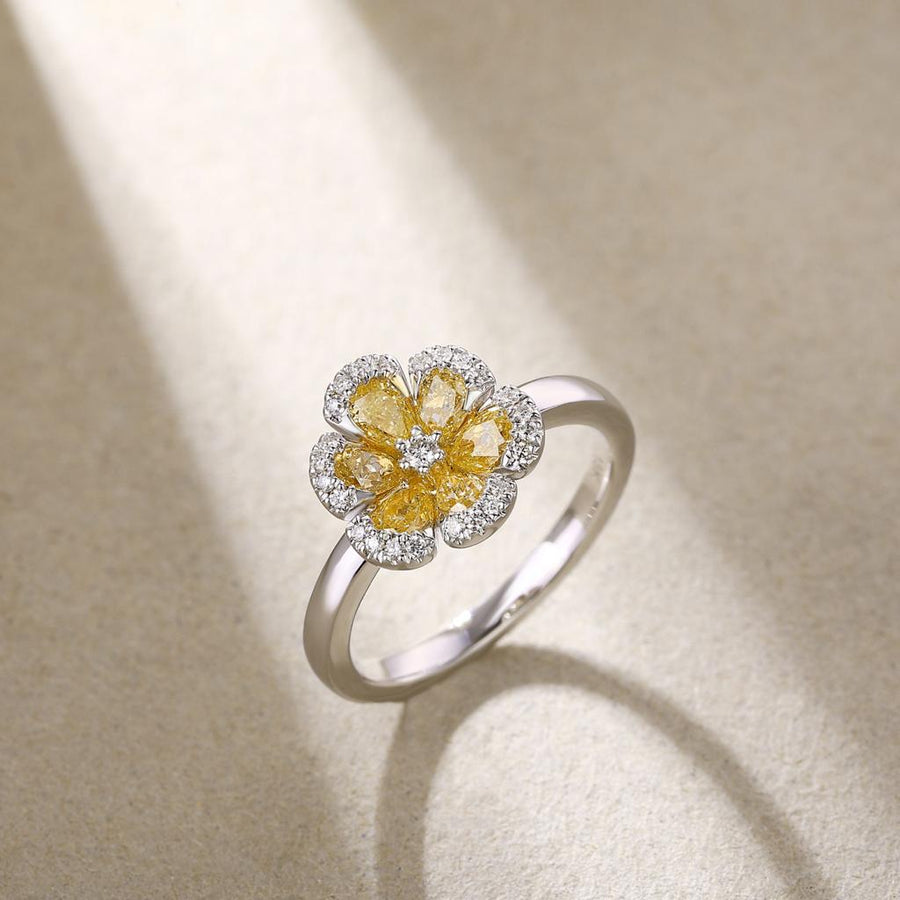 White gold floral diamond ring with yellow diamond cluster on a beige background