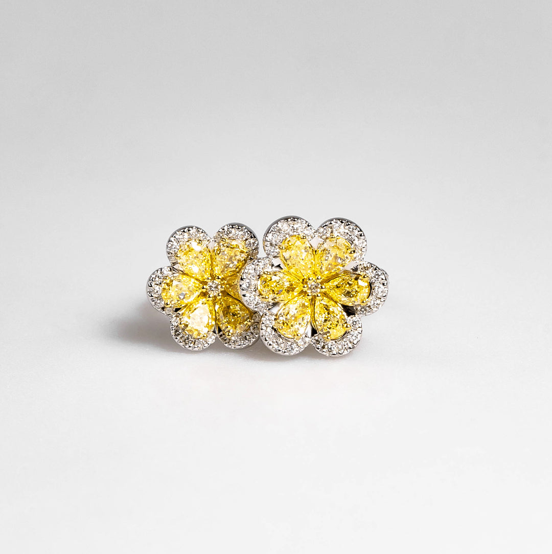 Yellow diamond flower cluster earrings with white diamond halos on a light gray background
