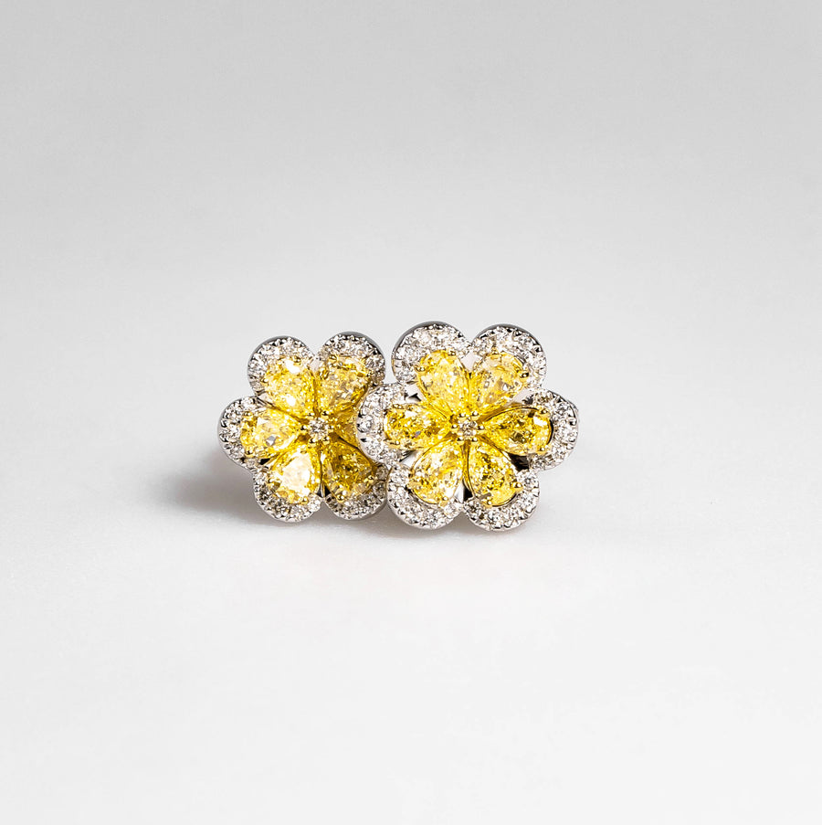 Yellow diamond flower cluster earrings with white diamond halos on a light gray background