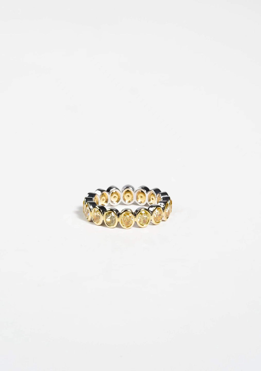Yellow gold eternity band with oval yellow gemstones set in bezel settings on a white background
