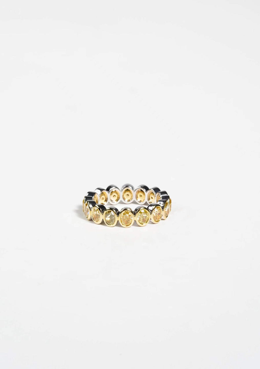 Yellow gold eternity band with oval yellow gemstones set in bezel settings on a white background