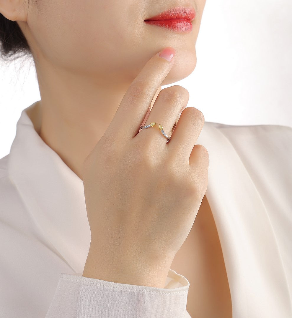 Close-up of a hand wearing a white gold open wrap ring with two yellow pear-cut diamonds and white diamond pave accents